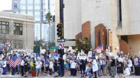 Cientos de personas se encuentran cerca del antiguo ayuntamiento de Tampa con carteles y banderas de protesta.