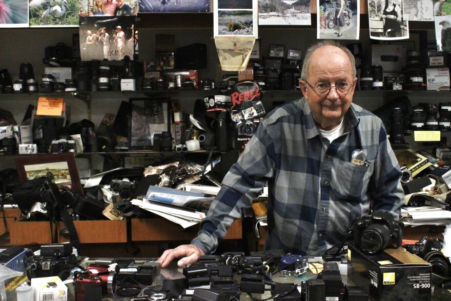 Gary Stitler stands behind the store's camera counter with a cornucopia of film and digital photography equipment.
