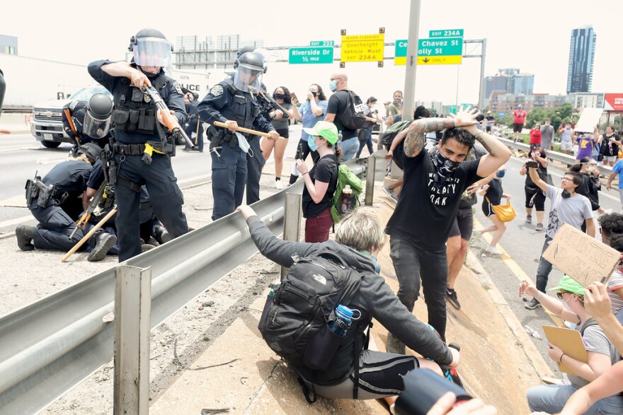 An Austin police officer points a shotgun equipped to fire so-called less lethal rounds at a demonstrator on I-35 in downtown Austin on May 30.