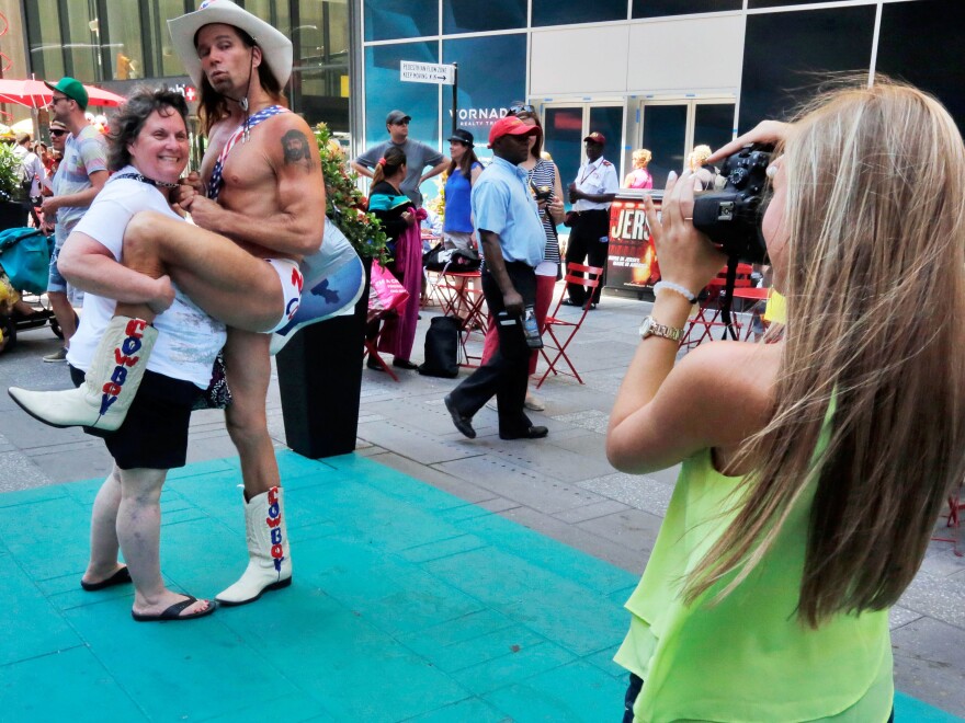 Robert Burck, The Naked Cowboy, poses for photos in one of Times Square's new color-coded designated activity zones in New York City. The new rules are aimed at controlling overly aggressive street performers. Violators face fines or jail time.