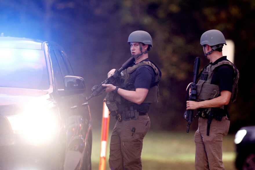 Law enforcement stand at the entrance to Neuse River Greenway Trail parking at Abington Lane following a shooting in Raleigh, N.C., Thursday, Oct. 13, 2022.