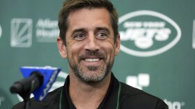FILE - New York Jets' quarterback Aaron Rodgers smiles during an NFL football news conference at the Jets' training facility in Florham Park, N.J., Wednesday, April 26, 2023. The New York Jets' first training camp with new quarterback Aaron Rodgers is getting the “Hard Knocks” treatment. The team announced its featured role on the long-running HBO and NFL Films show on Monday, July 17, 2023. (AP Photo/Seth Wenig, File)