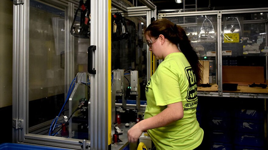 A worker at a factory in North Vernon, Indiana, works with a plastics manufacturing robot.