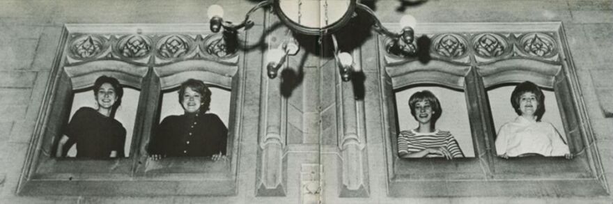 Four women peek out from a wall inside IU's campus