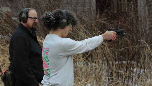 Matt Shepherd (left) watches as Erin Ramsby, a trans woman from Columbus, practices handling a gun.