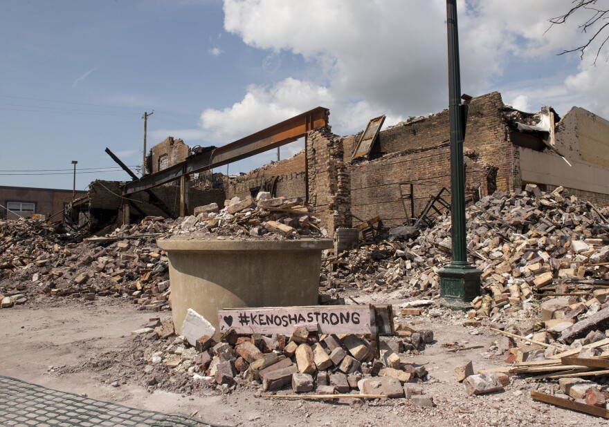 A sign stating "#KENOSHASTRONG" sits on a pile of bricks in front of a destroyed building in the Uptown neighborhood of Kenosha, WI.
