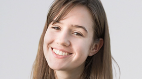 A smiling young woman has long brown hair.