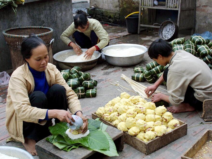 Members of a family are busy making the traditional lunar new year <em>banh chung</em>, or rice cakes, for sale on the courtyard of their house in Chanh Khuc village in suburban Hanoi.