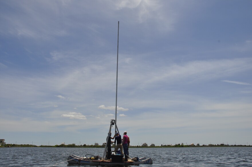 Scientists collect a sediment core from Salt Pond in Falmouth, MA. 