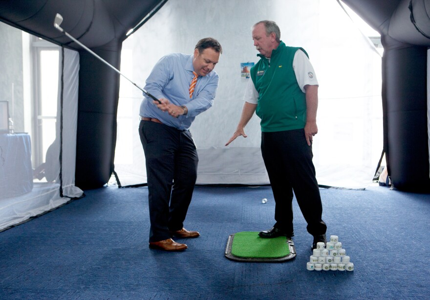 Eric Werwa, left, Deputy Chief of Staff for Rep. Mike Honda, D-Calif., gets some tips on his swing from a PGA professional at the National Golf Day event on Capitol Hill.