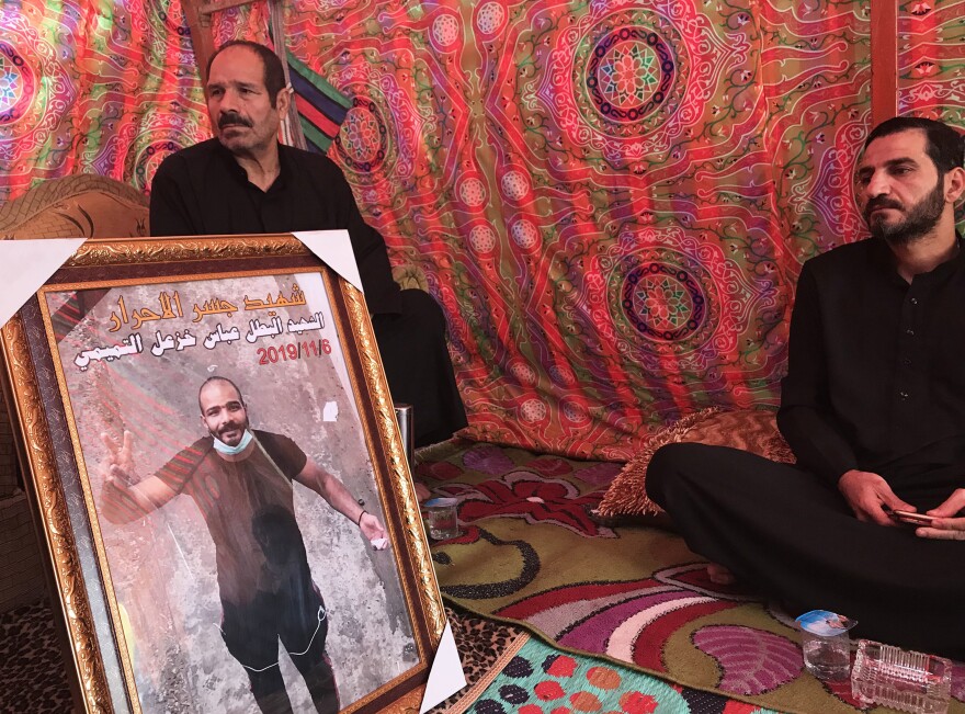 Mourners sit with a framed photo of Abbas Salih, who was shot dead Nov. 6.