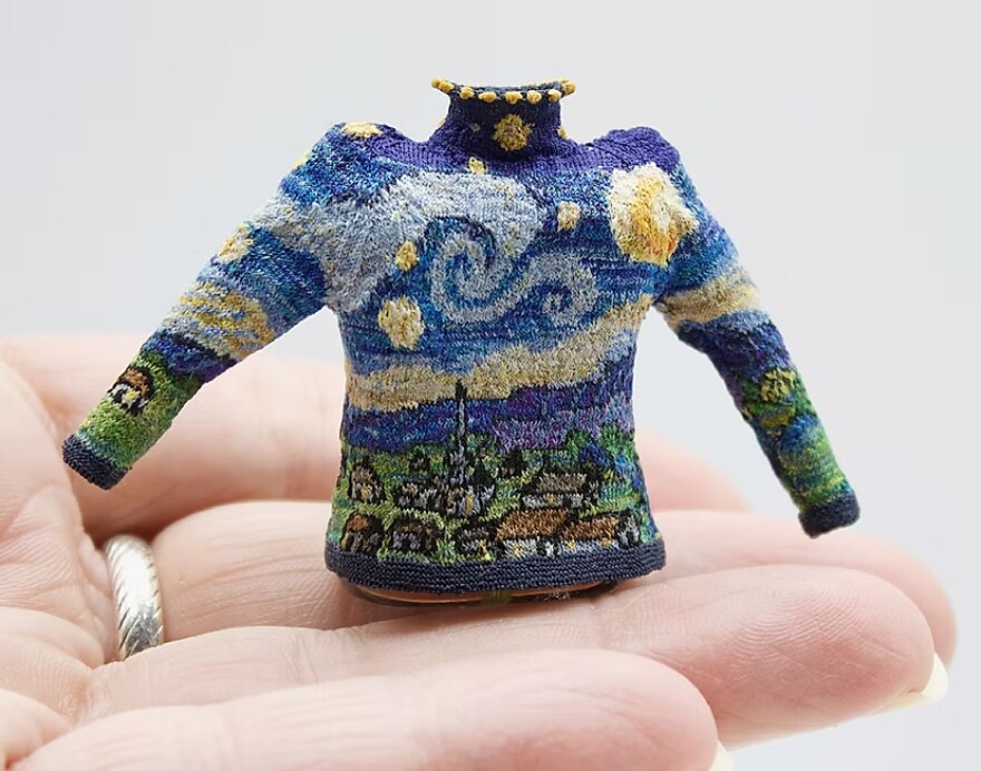 a tiny sweater knit with the pattern of the Van Gough painting Starry Night, sits in a persons hand.