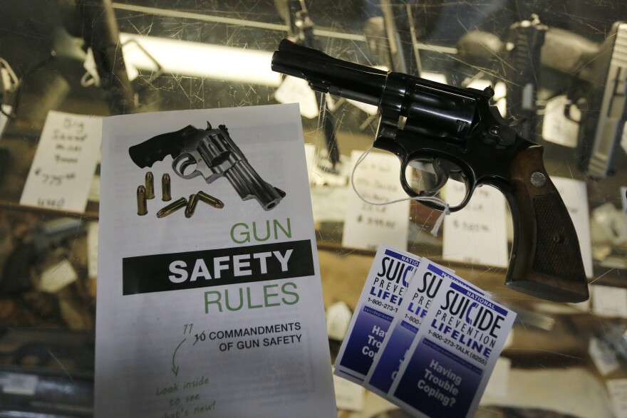 File - In this Feb. 23, 2016 file photo, gun safety and suicide prevention brochures are on display next to guns for sale at a local retail gun store in Montrose, Colorado.