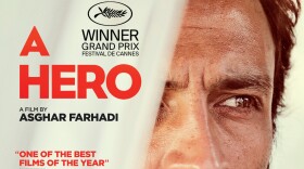 A film poster for “A Hero.” A close-up of a man’s face. He is looking away from the camera. There is an out-of-focus curtain in the foreground that partially covers the view of the right side of his face.