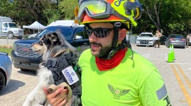 Moises Soffer, a volunteer member of Cadena International's search-and-rescue team working at the site of the condo building collapse, holds a trained search dog named Oreo in Surfside, Fla., on Sunday.