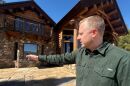 Man pointing at log cabin