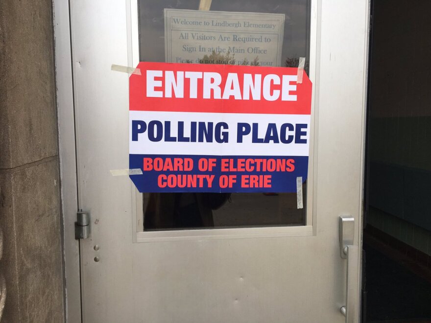 An "ENTRANCE POLLING PLACE BOARD OF ELECTIONS COUNTY OF ERIE" sign taped to a silver door.