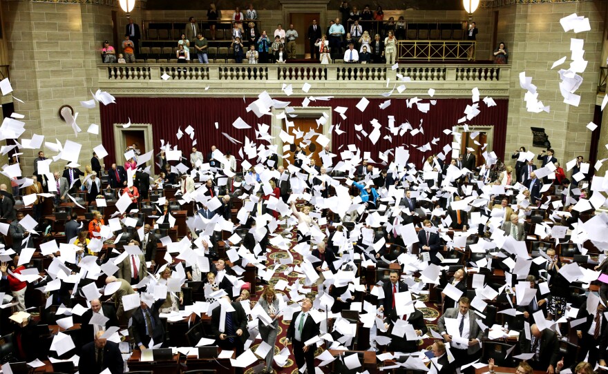 Members of the Missouri House of Representatives throw their papers in the air to mark the end of the legislative session on Friday in Jefferson City.