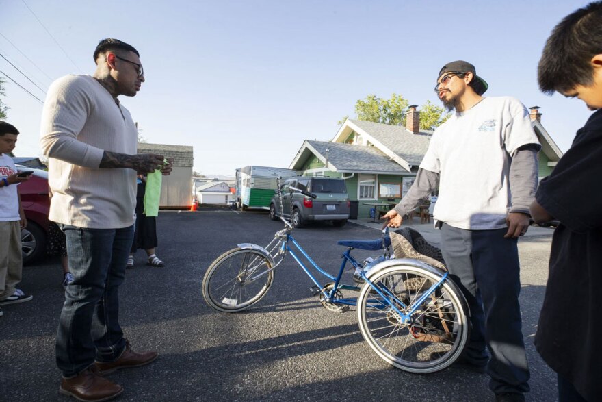 Valentin Mendoza, left, speaks with Ezzy Pina about a lowrider tricycle Thursday at the Community for the Advancement of Family Education (CAFÉ). (Credit: Jacob Ford / Wenatchee World)