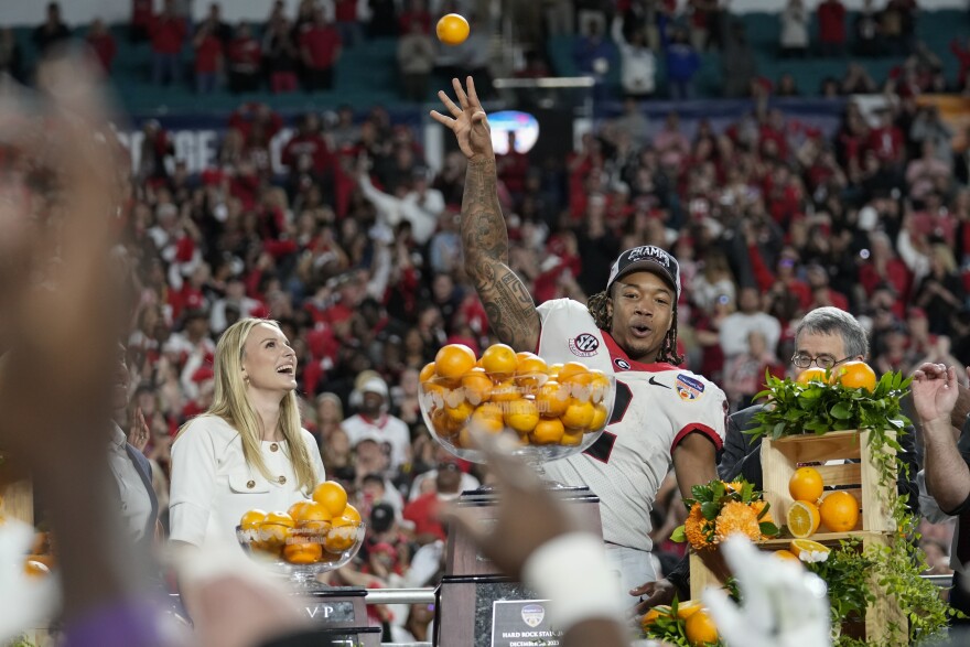 Georgia running back Kendall Milton, Orange Bowl MVP, throws oranges from the bowl trophy to teammates below, after Georgia defeated Florida State in the Orange Bowl NCAA college football game, Saturday, Dec. 30, 2023, in Miami Gardens, Fla. (AP Photo/Rebecca Blackwell)