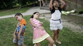 FILE - In this July 17, 2014 file photo, Darwin Ruiz, 5, left, his sister Jolleth Ruiz, 8, center, and their aunt, Ashley Orve, play in the front yard of the of the Ruiz' apartment building in Huntington Station, N.Y. While Darwin was born in the United States, Jolleth traveled to the United States from Nicaragua without her parents, but with her sister instead, in June of 2013. In November 2014, immigration activists are calling for funding to help provide legal services to the more than 3,000 children living in Long Island who crossed illegally into the U.S. without their parents. They say that only two non-profit organizations offer immigration attorneys to the minors in the area. (AP Photo/Seth Wenig, File)