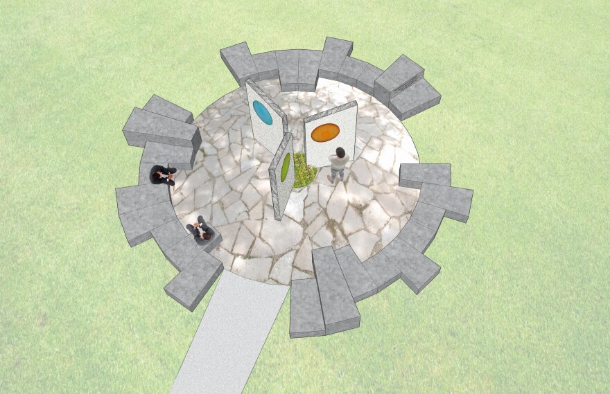 An aerial view of the memorial proposal rendering from Studiofolia featuring a stone circle with places to sit an a stone sculpture in  the middle with three panels. Each panel has a circular pane of colored glass