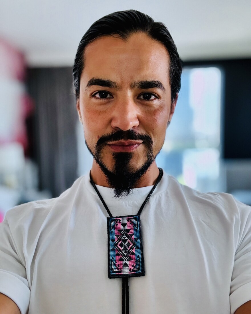 Man wearing a white shirt with a pink and blue rectangle bolo tie