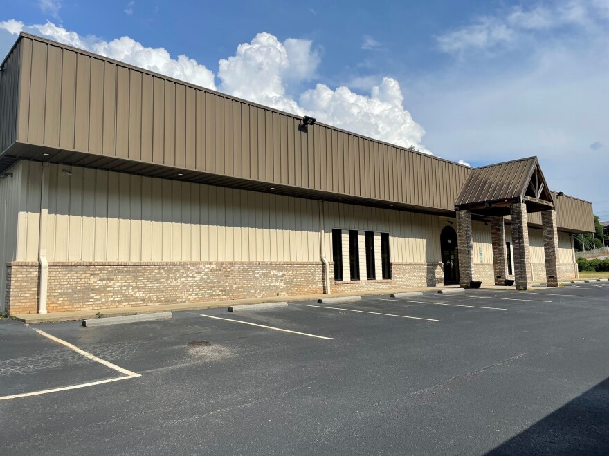 Shot from an angle, the facade of a large building off Highway 411 near Franklin where Vecinos plans to build a community health center. The building has brick and beige siding, and a brown roof. 