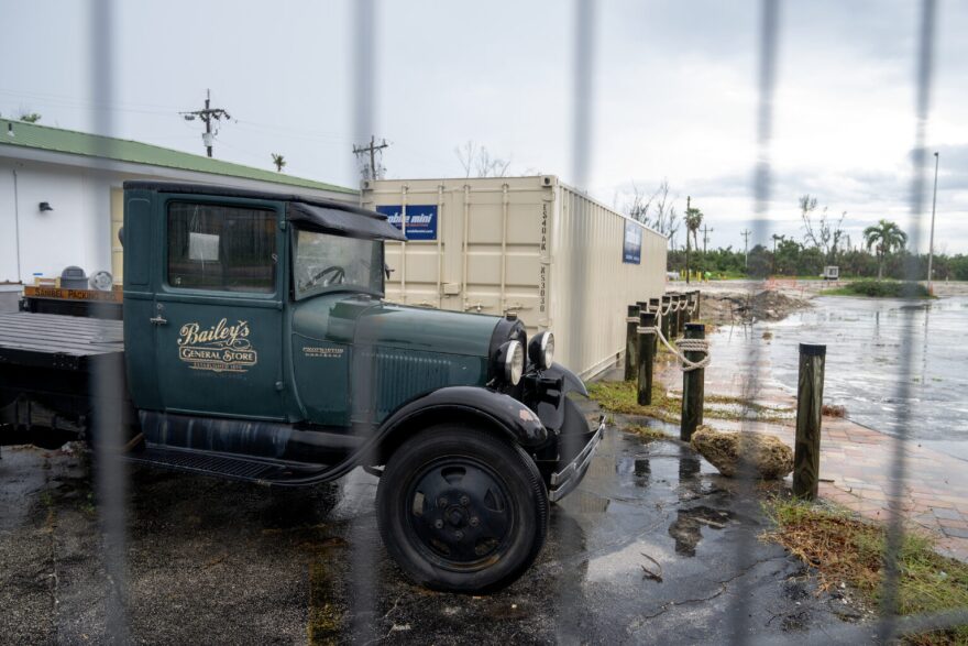 An antique Bailey’s General Store truck behind a fence.