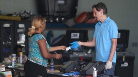 A poll worker in Miami Beach checks in George Hanley, who is wearing protective gloves, as he prepares to cast a ballot during the Florida presidential primary as the coronavirus pandemic continues.