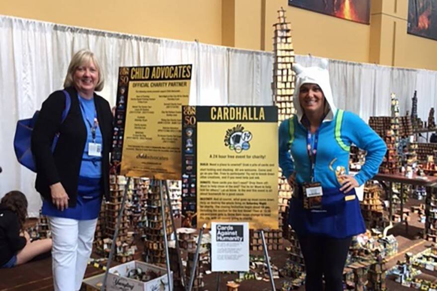 Child Advocates's Cindy Booth and Hannah Gentry stand in front of the Gen Con Cardhalla.