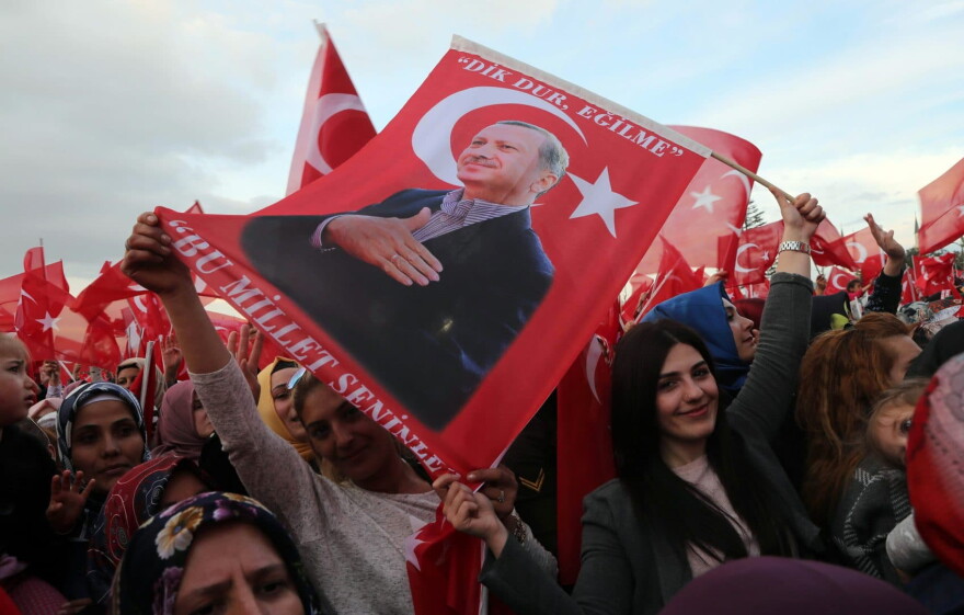 Supporters of the "yes" vote wave Turkish National flags and flags depicting Turkish president Recep Tayyip Erdogan as they cheer during his speech at the Presidential Palace in Ankara, on April 17, 2017, following the results in a nationwide referendum. (Adem Altan/AFP/Getty Images)