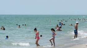 Beach goers take a dip in the Atlantic Ocean at Hollywood Beach, Monday, July 10, 2023, in Hollywood, Fla. Water temperatures in the mid-90s (mid-30s Celsius) are threatening delicate coral reefs, depriving swimmers of cooling dips and adding a bit more ick to the state's already oppressive summer weather. (AP Photo/Wilfredo Lee)