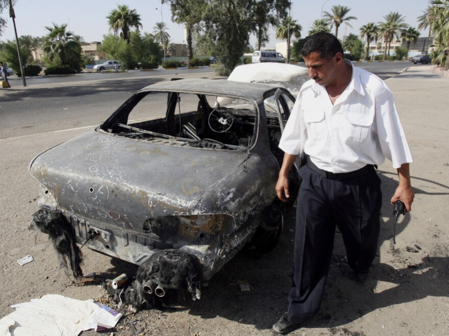 Sept. 20, 2007, file photo: An Iraqi traffic policeman inspects a car destroyed during the firefight four days earlier in Baghdad's al-Nisoor Square.