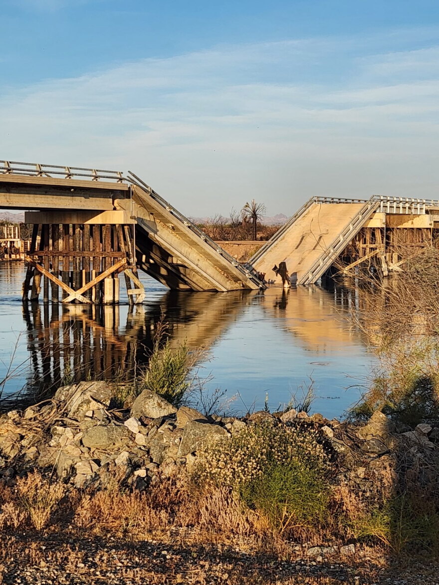 A cement and wood bridge broken in the middle and fallen into the water