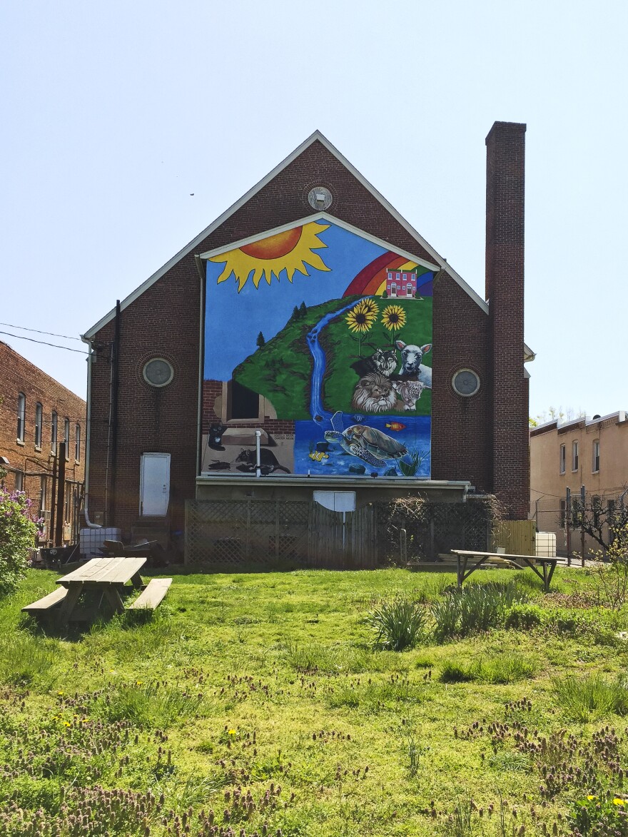 A large mural covers the back side of the Amazing Grace Lutheran Church in East Baltimore. It backs onto a park created by the Charm City Land Trust in an area where abandoned homes once stood.