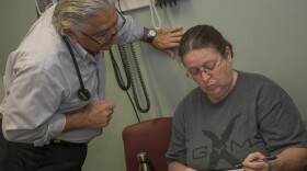 Dr. Ronald Cirillo helps Deborah Hatfield fill out paperwork at a Florida clinic, before running a test to see whether she has hepatitis C.