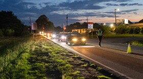 Cars lined up at night along the road during an ACCPD Checkpoint