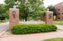 Brick entrance to Illinois Wesleyan University with a row of bushes in front of a sign