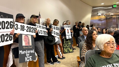 Protestors lined up along the walls of the board’s chambers, holding signs representing dates of ICE arrests at the County Jail.