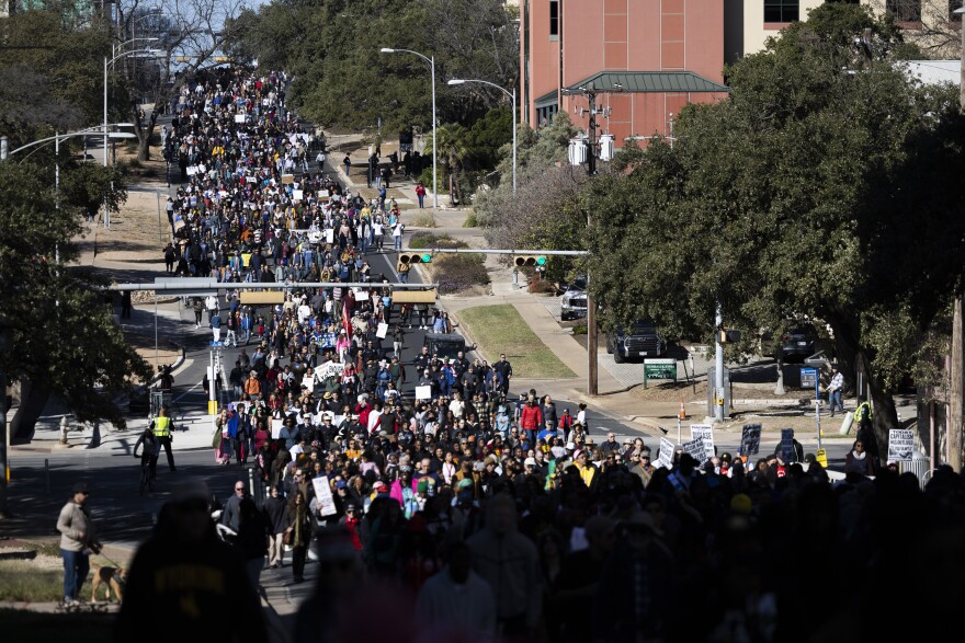 Hundreds of people are packed into a street marching.