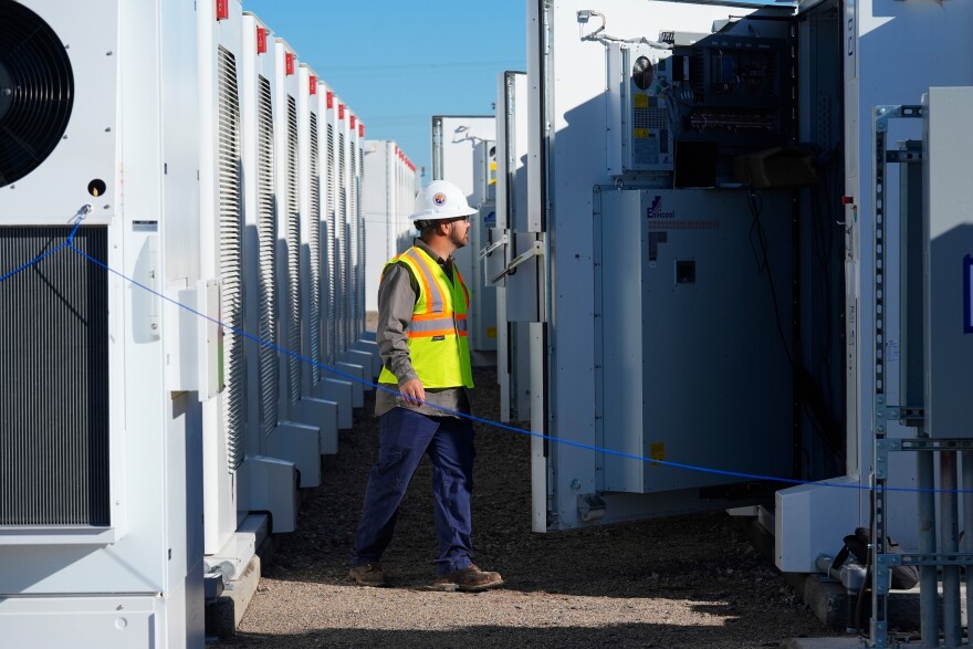 A worker does checks on battery storage pods at Orsted's Eleven Mile Solar Center lithium-ion battery storage energy facility Feb. 29, 2024, in Coolidge, Ariz. 