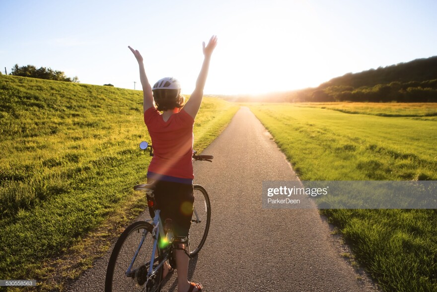 Woman Riding Her Bike Down Sunlit Trail