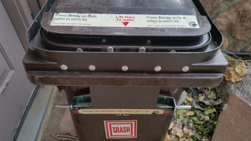 Image of a bear resistant trash can, displaying the instructions for use and the locking mechanism.