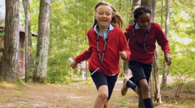 Two Interlochen Arts Camp students run through the woods. 