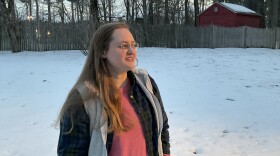 A woman stands in the snow looking into the distance