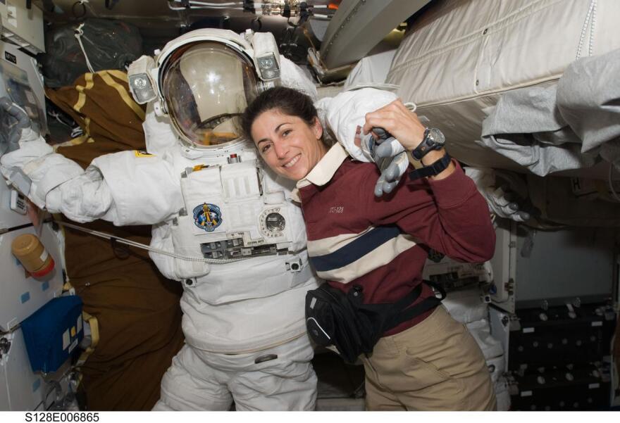 Astronaut Nicole Stott, STS-128 mission specialist, poses for a photo with an Extravehicular Mobility Unit (EMU) spacesuit on the middeck of the Space Shuttle Discovery during flight day three activities.