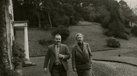 Max Mallowan and Agatha Christie walking side-by-side with hill and trees in background