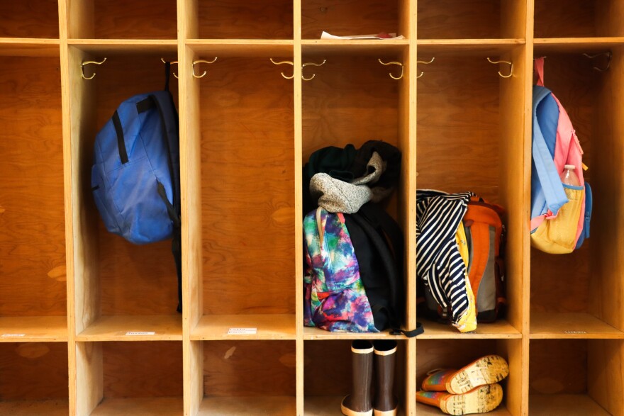 Backpacks and children's boots in wooden cubbyholes