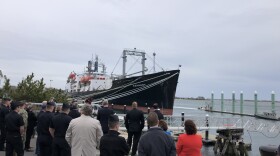 Cadets, state lawmakers and Governor Charlie Baker gather at Massachusetts Maritime Academy. In the distance, a training on how to mount a offshore wind turbine from a boat.